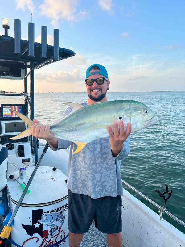 Smiling angler in sunglasses holding a jack crevalle fish on a fishing charter boat