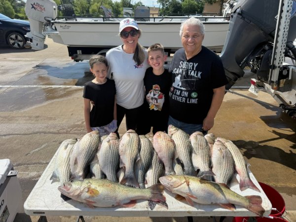 Family of four smiling behind a table full of striped bass caught on a fishing charter