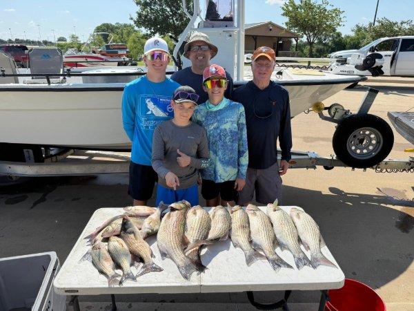 Family of five posing behind a table full of white bass caught during a fishing charter