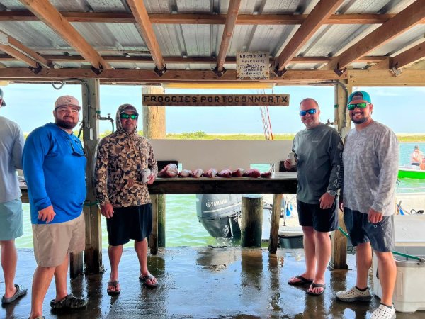 Four men standing under a dock at Froggies in Port OConnor Texas with fresh fish fillets on table
