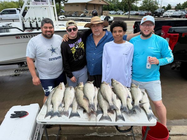 Five men posing with a table full of striped bass caught during a fishing charter trip