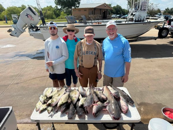 Four smiling anglers standing behind a table with a large catch of fish after a fishing charter